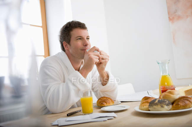Homem desfrutando de seu café da manhã na cozinha — Fotografia de Stock