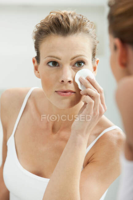 Mujer limpiando su cara en el baño - foto de stock