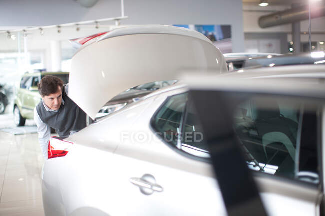 Uomo adulto medio che controlla lo stivale dell'automobile nello showroom dell'automobile — Foto stock