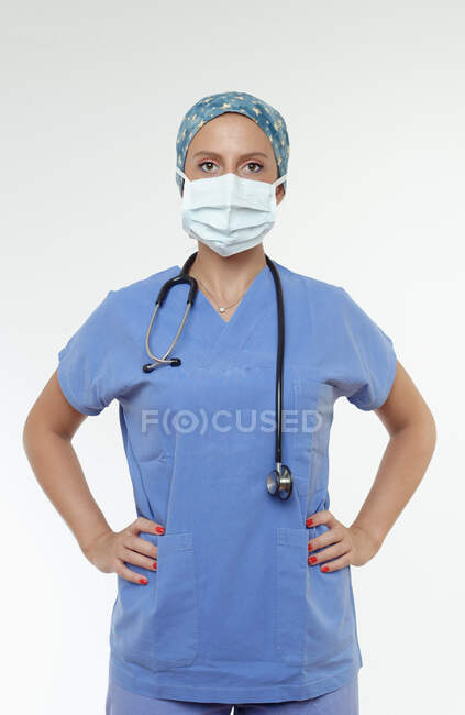 Хирург в хирургической маске, руки на бедрах смотрят в камеру — стоковое фото
