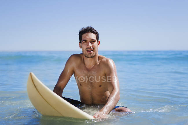 Hombre sentado en la tabla de surf en el agua - foto de stock