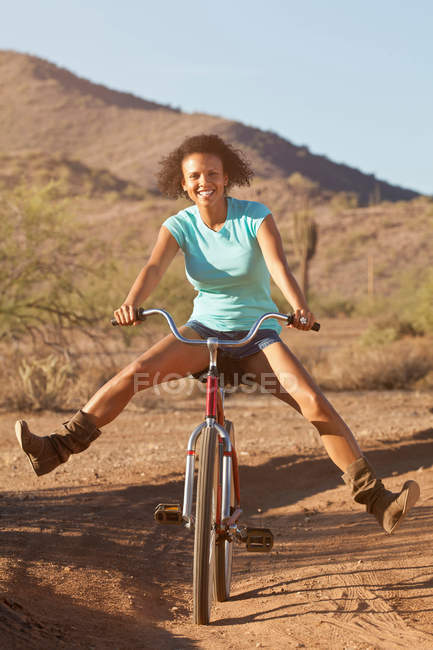 Woman on bicycle in desert landscape — Stock Photo