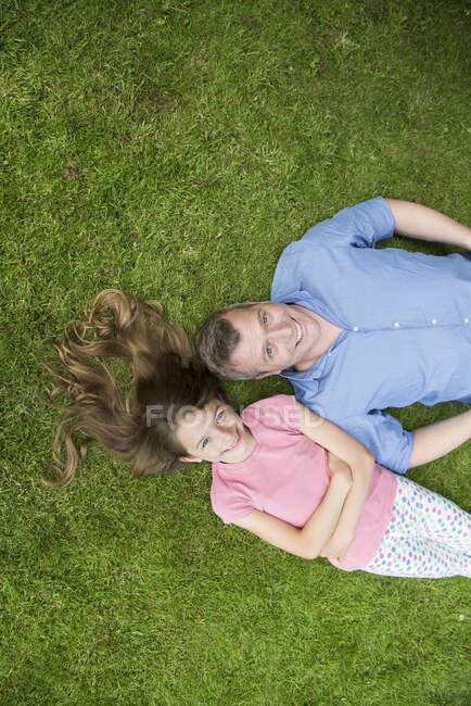 Pai e filha deitado na grama — Fotografia de Stock