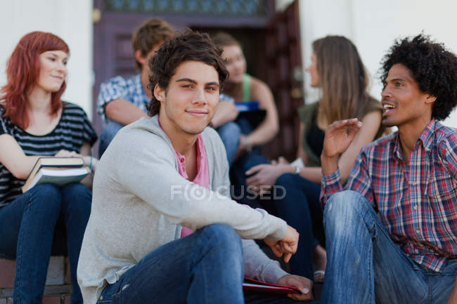 Studenten sitzen zusammen auf dem Campus — Stockfoto