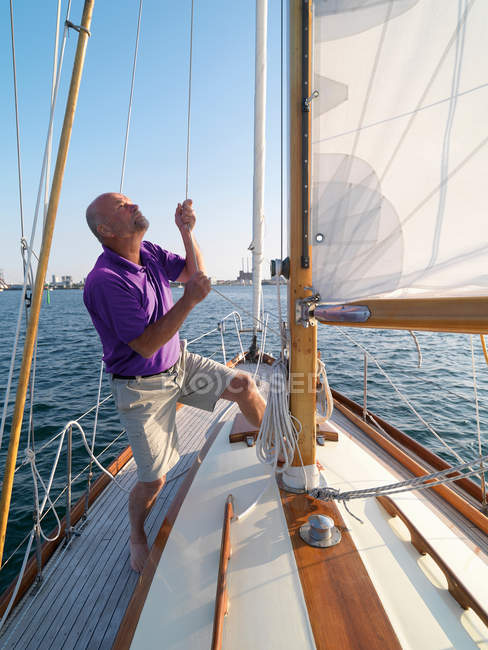 Uomo regolazione sartiame su barca a vela — Foto stock