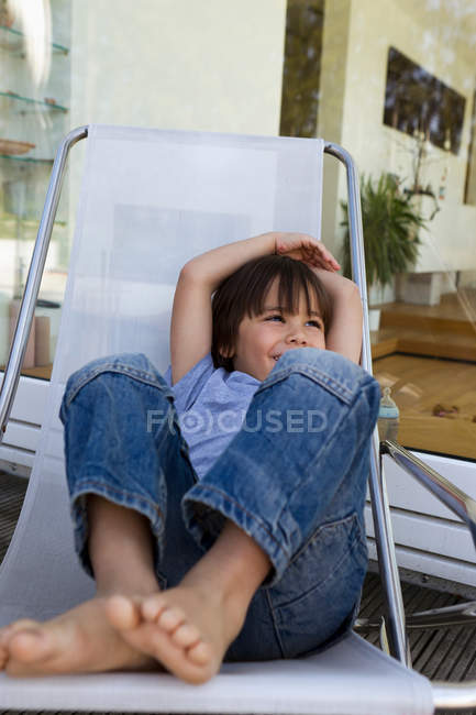 Menino relaxante na cadeira deck no pátio — Fotografia de Stock