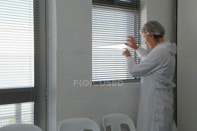 Factory worker peeping through blind — Stock Photo
