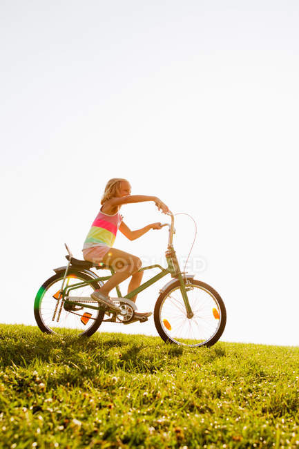 Mädchen reitet Fahrrad im Gras — Stockfoto