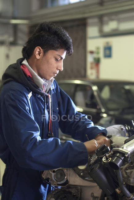 Student working on car engine, focus on foreground — Stock Photo