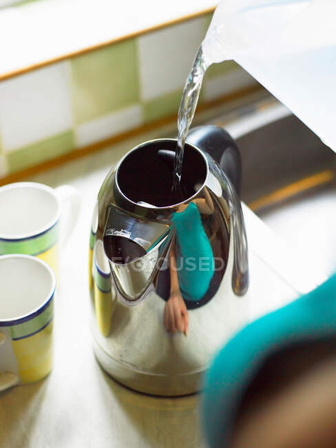 Woman pouring water into kettle — Stock Photo