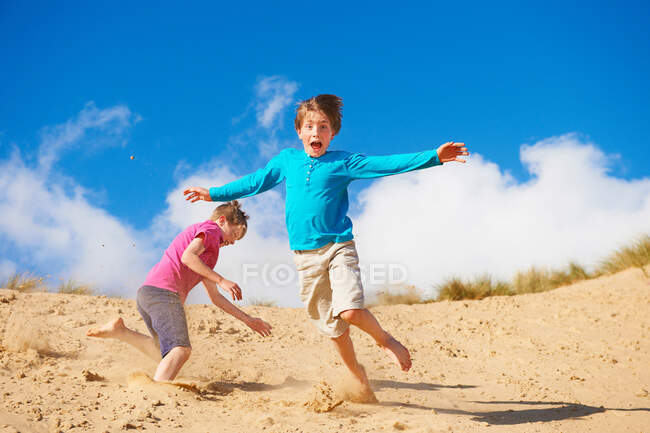Два хлопця біжать по піщаній дюні. — стокове фото