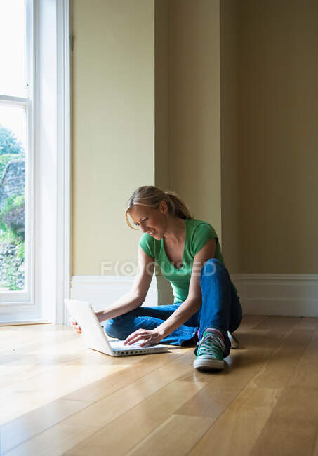 Жінка використовує ноутбук на підлозі — стокове фото