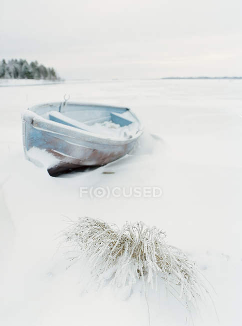 Barco amarrado en campo cubierto de nieve - foto de stock