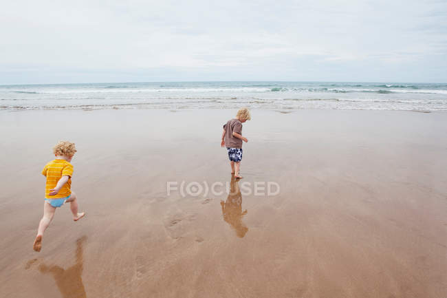 Niños jugando en olas en la playa - foto de stock