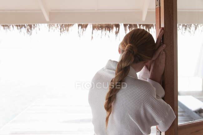 Mujer en albornoz de pie en la puerta - foto de stock