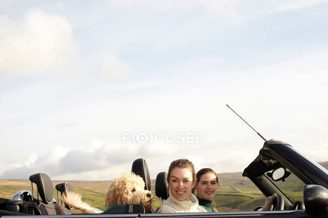 Жінки і собака за кермом в сільському пейзажі — стокове фото