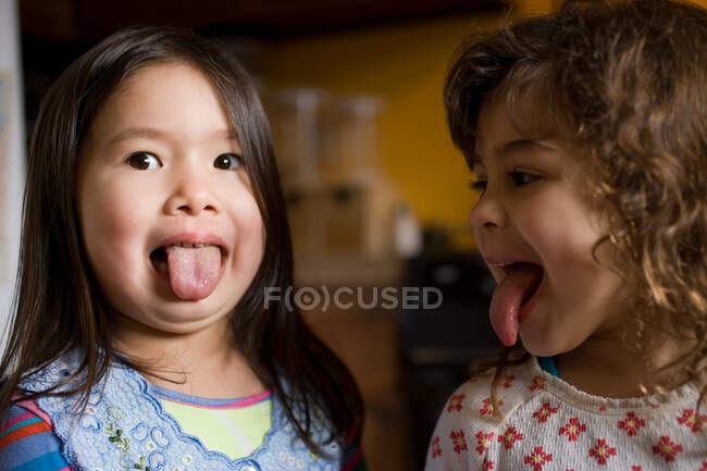 Dos chicas jóvenes sobresaliendo de sus lenguas - foto de stock