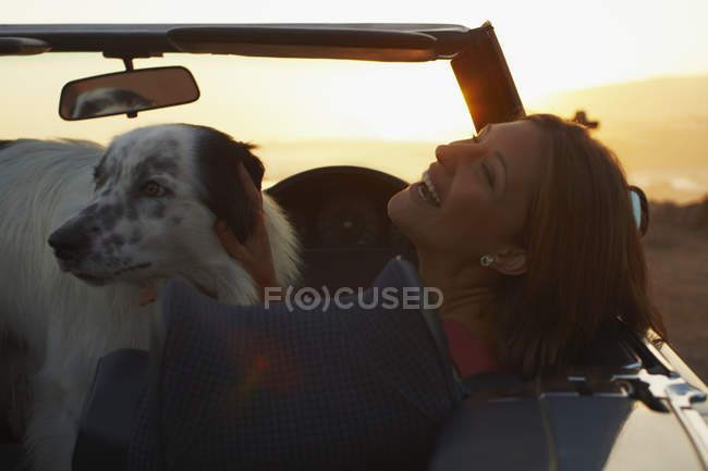 Frau lacht mit Hund im Cabrio — Stockfoto