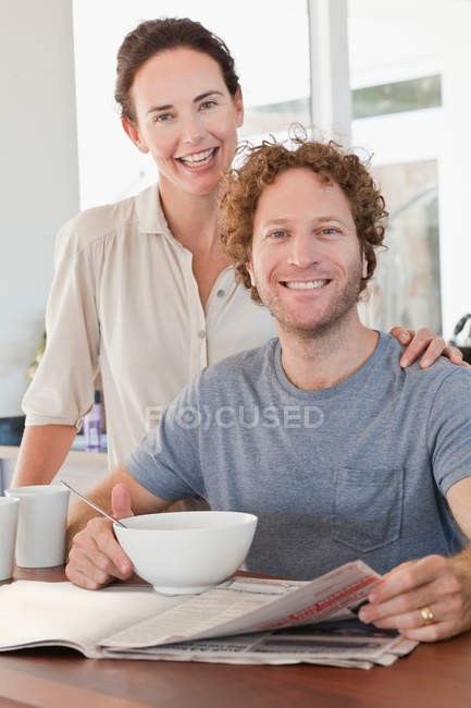 Couple reading newspaper at breakfast — Stock Photo