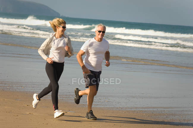 Paar läuft am Strand — Stockfoto