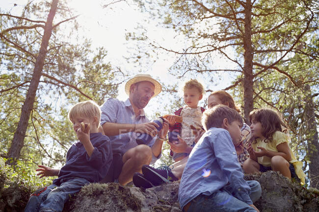 Familia de picnic sentado en las rocas - foto de stock
