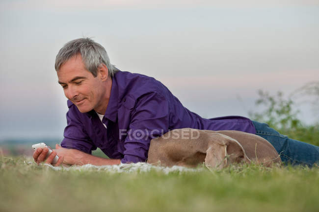 Man with dog checking smart phone — Stock Photo