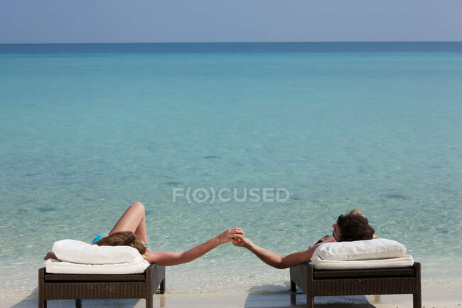 Пара розслабляється на ліжках на пляжі — стокове фото