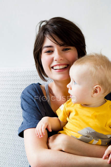 Mãe e bebê sentados na cama — Fotografia de Stock