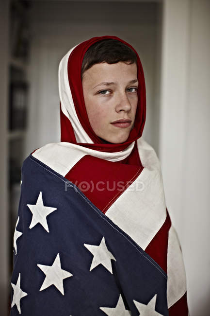 Menino segurando bandeira americana dentro de casa — Fotografia de Stock