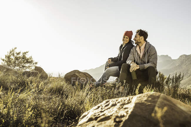Couple assis sur des rochers dans le champ — Photo de stock