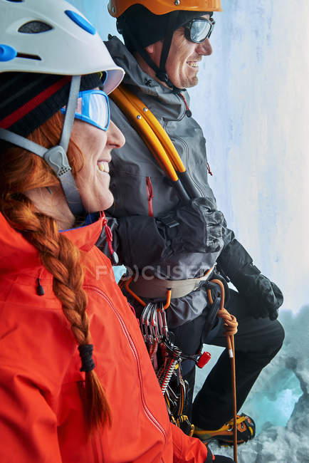 Escaladores de hielo en cueva de hielo mirando hacia otro lado sonriendo - foto de stock