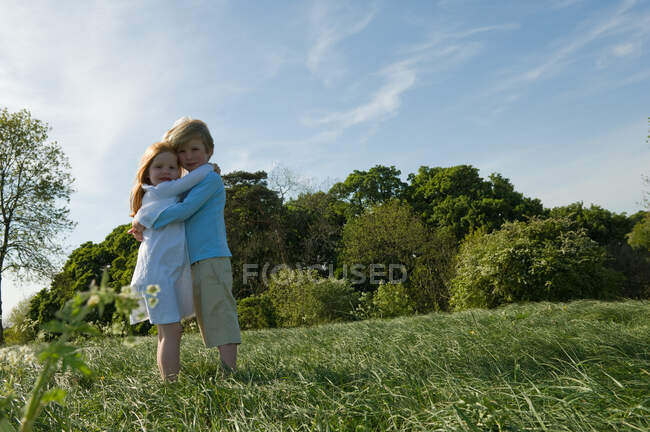 Niños abrazándose en el campo - foto de stock
