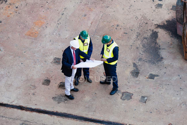 Рабочие читают чертежи в сухом доке — стоковое фото