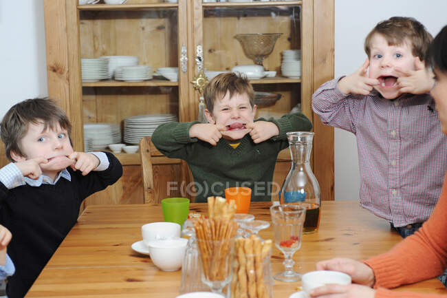 Мальчики корчат рожи за столом — стоковое фото