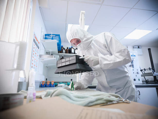 Scientifique légiste prélever des échantillons de sang dans les vêtements en laboratoire — Photo de stock