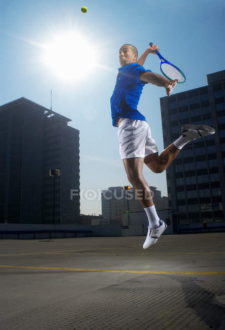 Tennis player jumping on rooftop court — Stock Photo