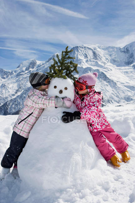 Dos chicas con muñeco de nieve - foto de stock
