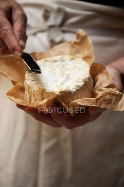Imagen recortada de hombre rebanando queso camembert - foto de stock