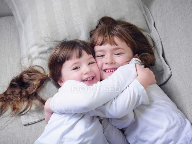 Girls hugging on sofa together — Stock Photo