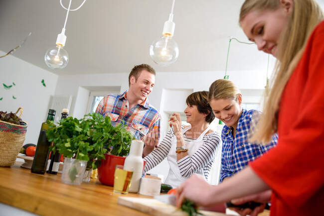 Mother with grown up children preparing food in kitchen — Stock Photo