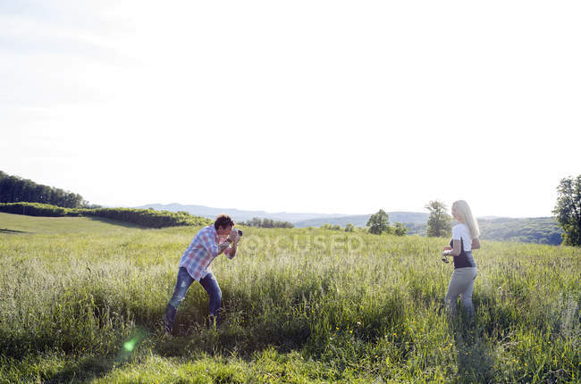 Man photographing woman in field — Stock Photo