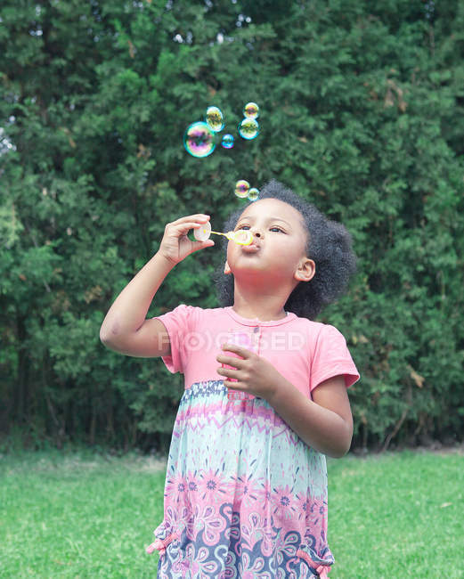 Chica soplando burbujas al aire libre - foto de stock