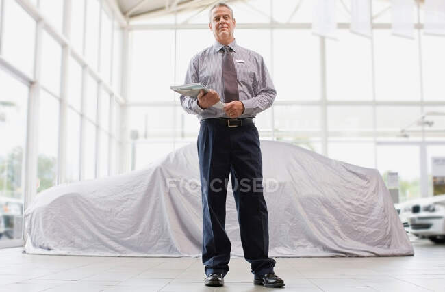 Vendedor de carros em pé no showroom — Fotografia de Stock