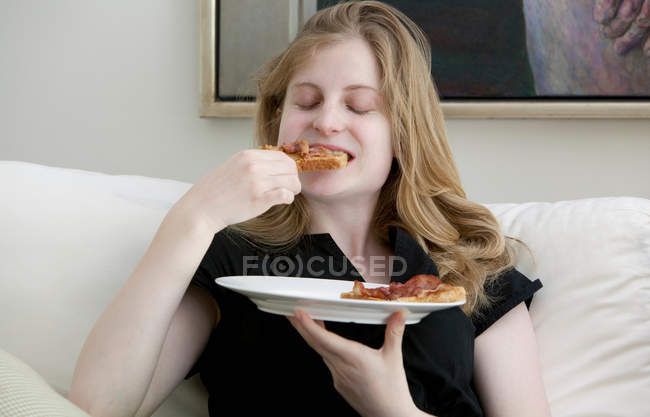 Adolescente ragazza mangiare sul divano — Foto stock