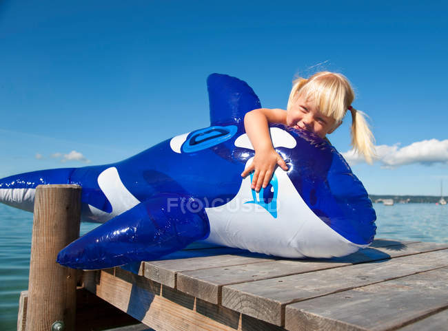 Menina segurando baleia inflável na doca — Fotografia de Stock