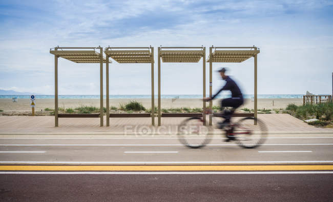 Размытое движение велосипедиста по прибрежной дороге, Кальяри, Италия — стоковое фото