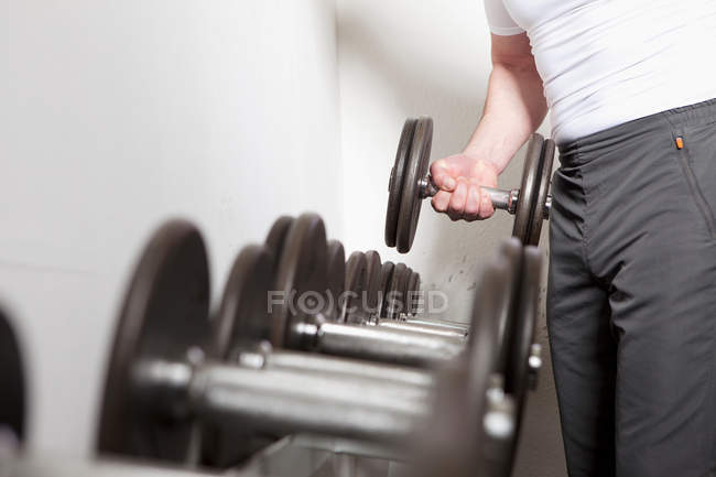Homme utilisant des poids libres à la salle de gym — Photo de stock