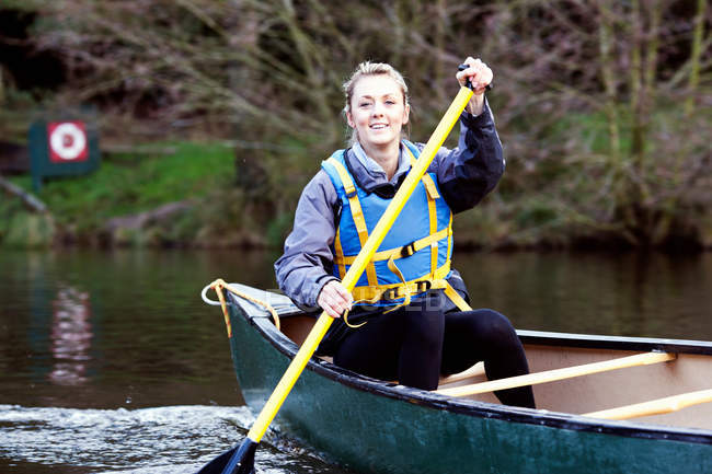 Woman rowing canoe on still lake — Stock Photo