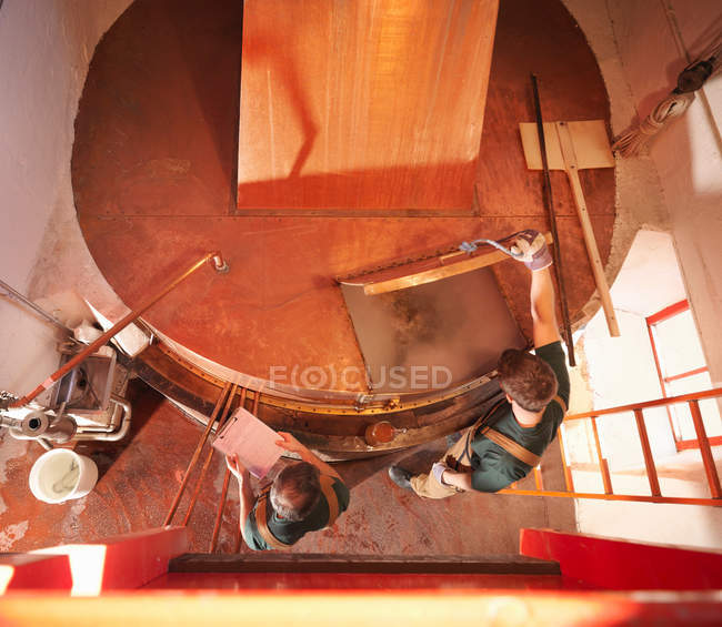 Trabajadores en tanque de cobre en cervecería - foto de stock