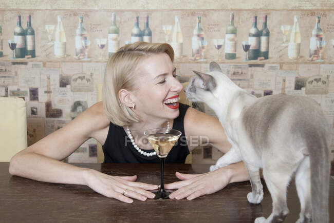 Mujer bebiendo martini con gato - foto de stock